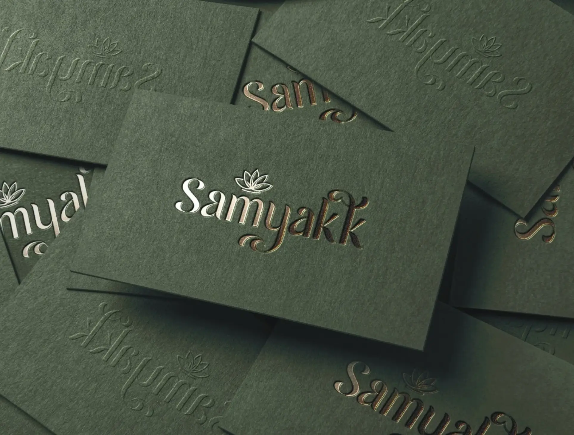 Green Samyakk cards with the logo embossed and foiled, scattered on a table
